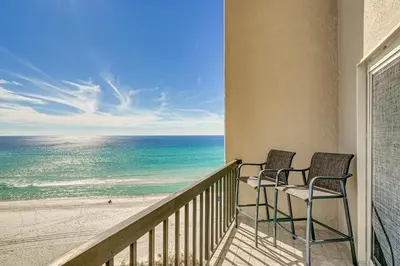 two chairs sitting on a balcony overlooking the beach at Steps to Shore! PCB Resort Condo with Balcony in Panama City Beach