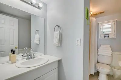 a white bathroom with a sink and a toilet at Steps to Shore! PCB Resort Condo with Balcony in Panama City Beach