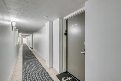 a hallway with white walls and a black and white floor at Steps to Shore! PCB Resort Condo with Balcony in Panama City Beach