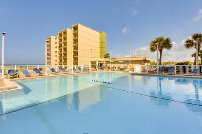 a large swimming pool with chairs and a hotel at Steps to Shore! PCB Resort Condo with Balcony in Panama City Beach