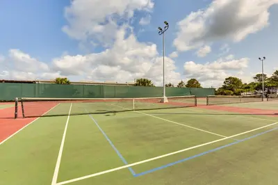 a tennis court with a tennis net on it at Steps to Shore! PCB Resort Condo with Balcony in Panama City Beach
