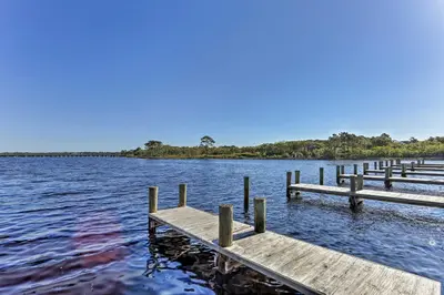 a dock on a lake with trees in the background at Steps to Shore! PCB Resort Condo with Balcony in Panama City Beach