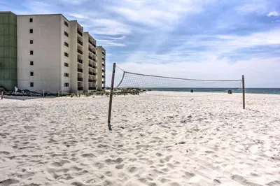 a volleyball net on a sandy beach next to a building at Steps to Shore! PCB Resort Condo with Balcony in Panama City Beach