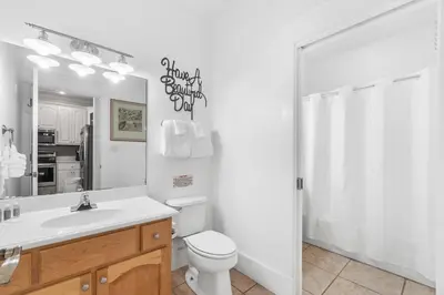 a bathroom with a toilet and a sink and a mirror at Panama City Beach House - Sunnyside Up in Panama City Beach