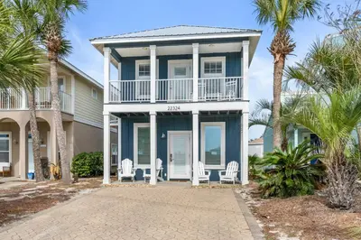 a house with palm trees in front of it at Panama City Beach House - Sunnyside Up in Panama City Beach