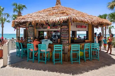 a bar with chairs and a straw umbrella on the beach at Calypso Beach Resort Towers in Panama City Beach