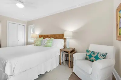 a white bedroom with a bed and a chair at Double Down in Santa Rosa Beach