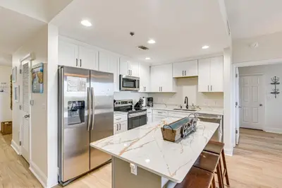 a kitchen with white cabinets and a stainless steel refrigerator at Comfy PCB Condo with View and Private Beach Access! in Panama City Beach