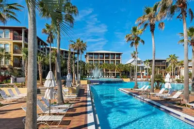 a pool at the resort with lounge chairs and palm trees at La Dolce Vita in Inlet Beach