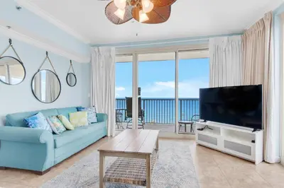 a living room with a blue couch and a flat screen tv at Shores of Panama 1401 in Panama City Beach