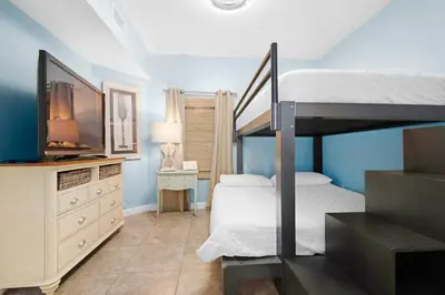 a bedroom with a bunk bed and a tv at Shores of Panama 1401 in Panama City Beach