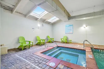 a pool in a room with green chairs and a table at Shores of Panama 1401 in Panama City Beach