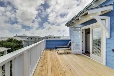 a balcony with a bench on a blue house at Amazing Place - 1232960 in Santa Rosa Beach
