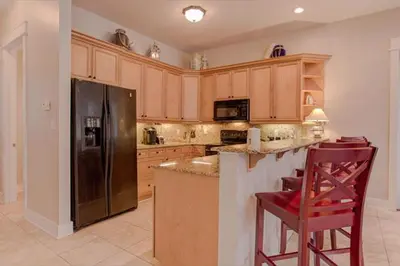 a kitchen with wooden cabinets and a black refrigerator at Amazing Place - 1232960 in Santa Rosa Beach