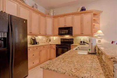 a kitchen with wooden cabinets and a black refrigerator at Amazing Place - 1232960 in Santa Rosa Beach