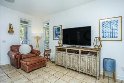 a living room with a television and a chair at DRIFTWOOD COTTAGE at Seacrest Beach - 1581803 in Panama City Beach