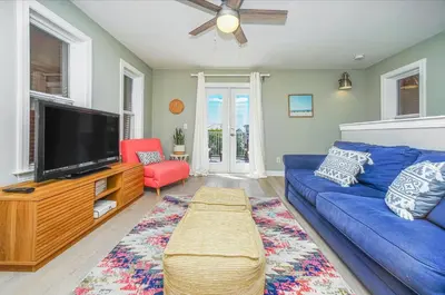 a living room with a blue couch and a tv at DRIFTWOOD COTTAGE at Seacrest Beach - 1581803 in Panama City Beach