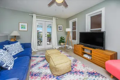 a living room with a blue couch and a flat screen tv at DRIFTWOOD COTTAGE at Seacrest Beach - 1581803 in Panama City Beach