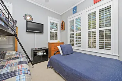 a bedroom with a bed and a tv and windows at Happy Hour - 1232970 in Rosemary Beach