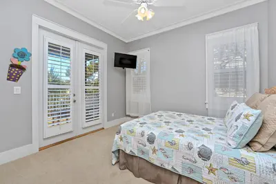 a bedroom with a bed and a tv and windows at Happy Hour - 1232970 in Rosemary Beach