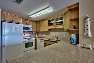 a kitchen with a white refrigerator and wooden cabinets at Pirate Cove Villa 117 - 825255 in Panama City Beach