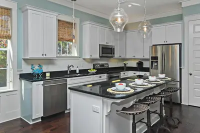 a kitchen with white cabinets and a black counter top at Seas The Day at Seacrest - 1228999 in Panama City Beach