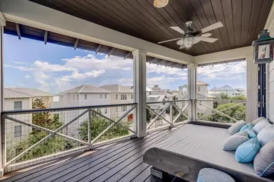 a balcony with a couch and a ceiling fan at The White House - 1232985 in Santa Rosa Beach