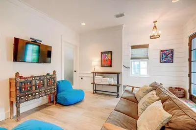 a living room with a couch and a tv at The White House - 1232985 in Santa Rosa Beach
