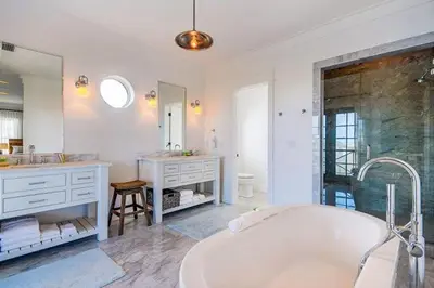 a bathroom with a tub and a sink and a mirror at The White House - 1232985 in Santa Rosa Beach