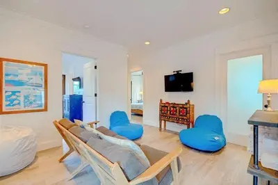 a living room with a couch and blue chairs at The White House - 1232985 in Santa Rosa Beach