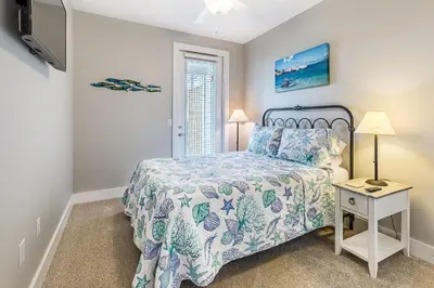a bedroom with a bed and a night stand with a table at Inn to the Mystic in Santa Rosa Beach
