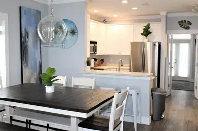 a kitchen and dining room with a table and a refrigerator at Beach Beyond Belief House & private pool & free bikes & private beach in Rosemary Beach