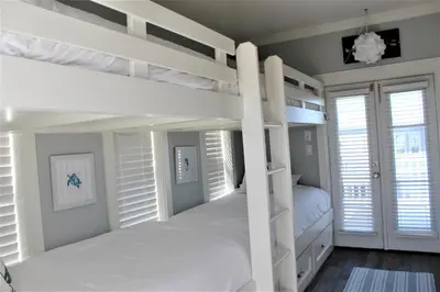 a bedroom with two bunk beds and white shuttered windows at Beach Beyond Belief House & private pool & free bikes & private beach in Rosemary Beach