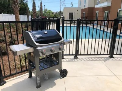 a grill sitting next to a fence next to a pool at Candlewood Suites - Panama City Beach Pier Park by IHG in Panama City Beach