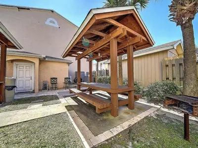 a wooden pergola with a bench in front of a house at Merrimac Resort #32 in Panama City Beach