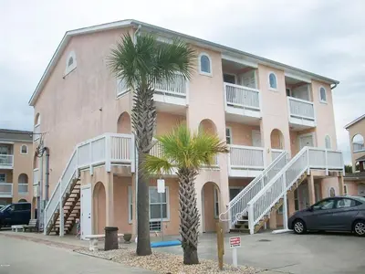 a building with two palm trees in front of it at Merrimac Resort #32 in Panama City Beach
