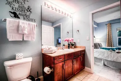 a bathroom with a sink and a toilet and a mirror at Laketown Wharf 534 By Aneliya in Panama City Beach