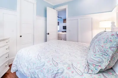 a white bedroom with a bed with a colorful bedspread at Stay Salty in Santa Rosa Beach