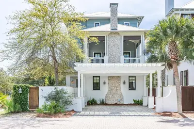 a white house with a gate and palm trees at Stay Salty in Santa Rosa Beach
