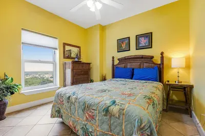 a bedroom with a bed with yellow walls and a window at Ocean Reef 1709 in Panama City Beach