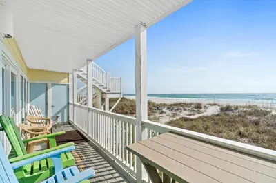 a porch with chairs and a table and the beach at Harbur Arms - Pet Friendly in Panama City Beach