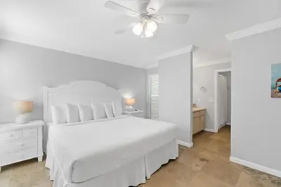 a white bedroom with a white bed and a ceiling fan at Harbur Arms - Pet Friendly in Panama City Beach