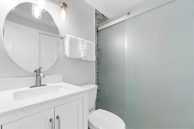 a white bathroom with a sink and a mirror at Harbur Arms - Pet Friendly in Panama City Beach