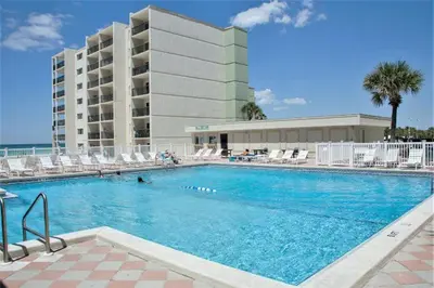 a large swimming pool with chairs and a building at Pinnacle Port Beach Resort in Panama City Beach