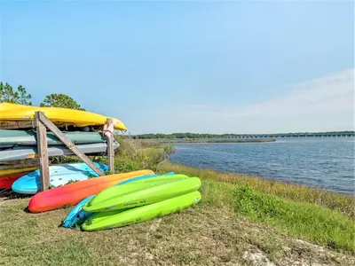 a group of kayaks sitting on the grass near the water at Pinnacle Port Beach Resort in Panama City Beach