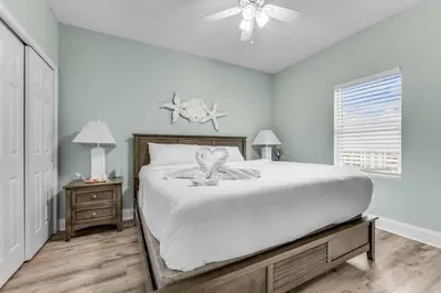 a white bedroom with a bed and a ceiling fan at Laketown Wharf 1331 in Panama City Beach