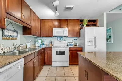 a kitchen with wooden cabinets and a white refrigerator at Laketown Wharf 1331 in Panama City Beach