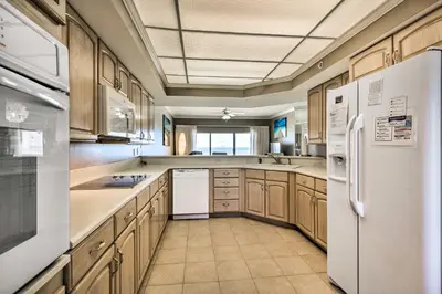 a large kitchen with wooden cabinets and white appliances at Gulf Views and Pool Access Coral Reef Resort Condo in Panama City Beach