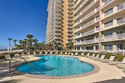 a swimming pool with lounge chairs and a large building at Gulf Views and Pool Access Coral Reef Resort Condo in Panama City Beach