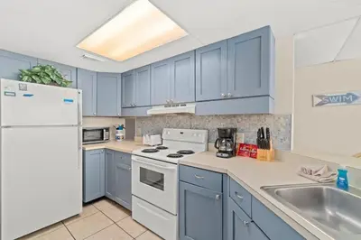 a kitchen with blue cabinets and a white refrigerator at Aquavista 405e in Panama City Beach